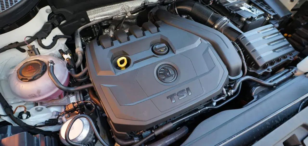 Motor 1.5 TSI 150cv, con su tapa negra y logo Skoda. Se aprecian manguitos y depósito de refrigerante.