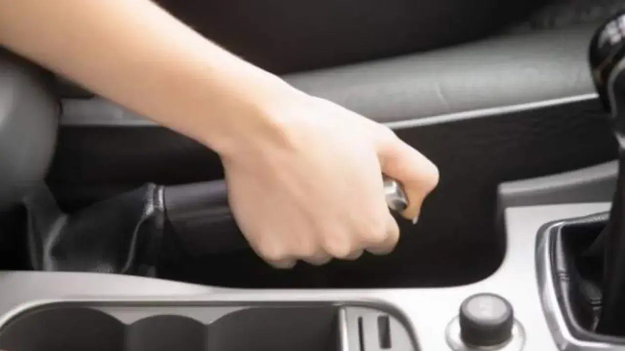 Mano tensando el freno de mano de un Volvo XC90.