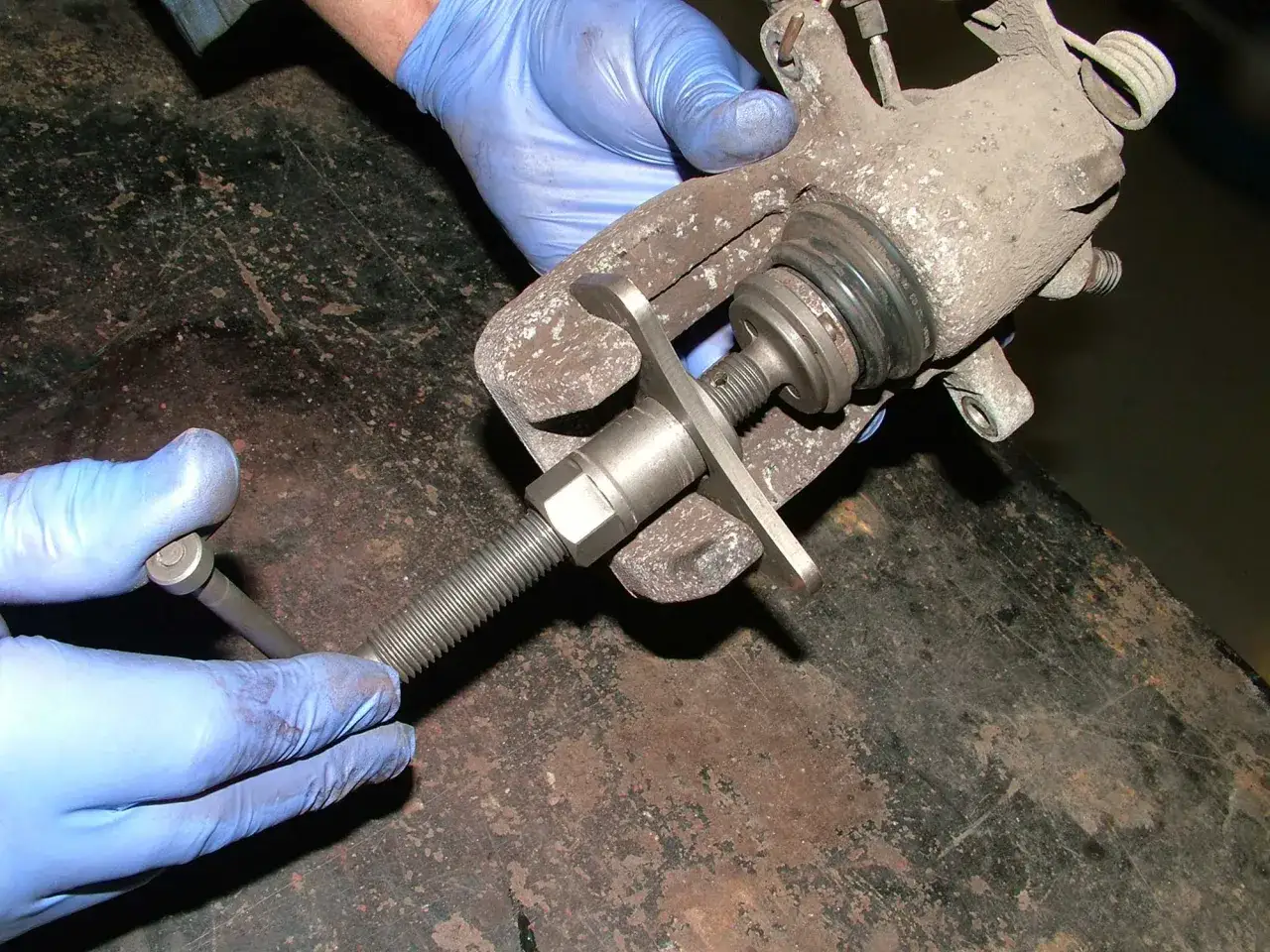 Mec&aacute;nico usa herramienta para empujar el pist&oacute;n de la pinza de freno, que no retrocede.