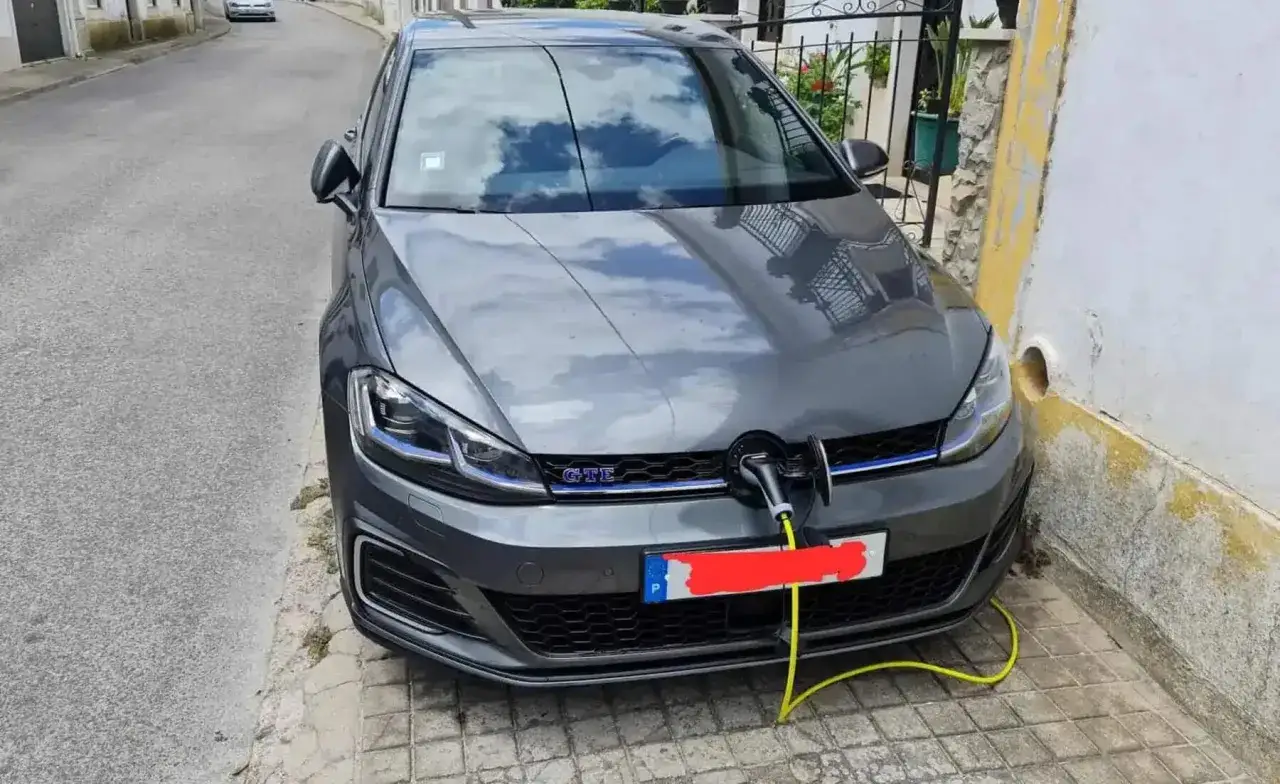 Un coche h&iacute;brido gris Volkswagen Golf GTE se est&aacute; cargando con un cable amarillo conectado a la parrilla.