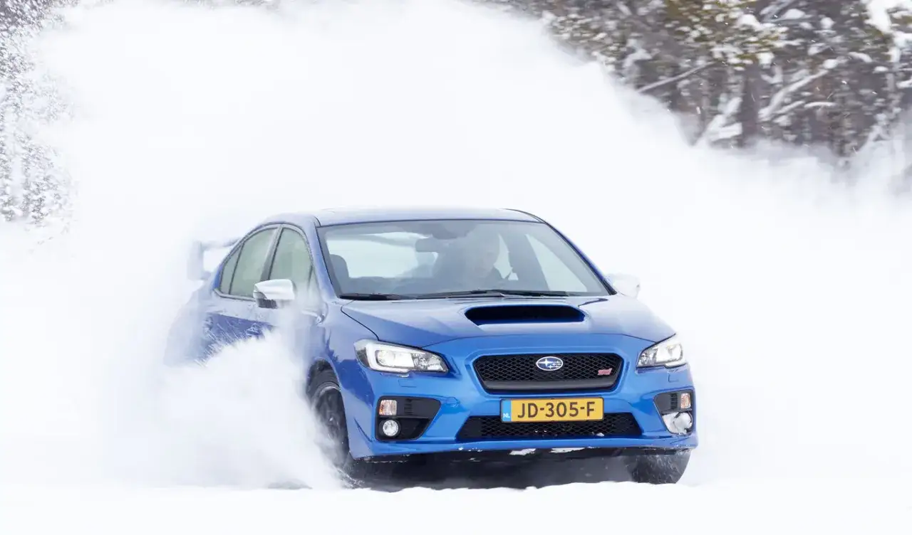 Un coche azul derrapa en la nieve, mostrando cu&aacute;nto aumenta la distancia de frenado con hielo.