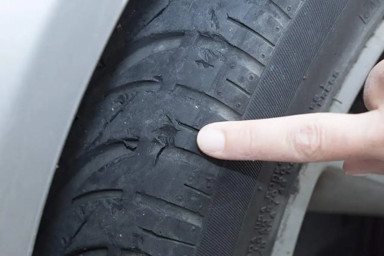 Dedo se&ntilde;ala un neum&aacute;tico por dentro con grietas y desgaste severo, indicando peligro.