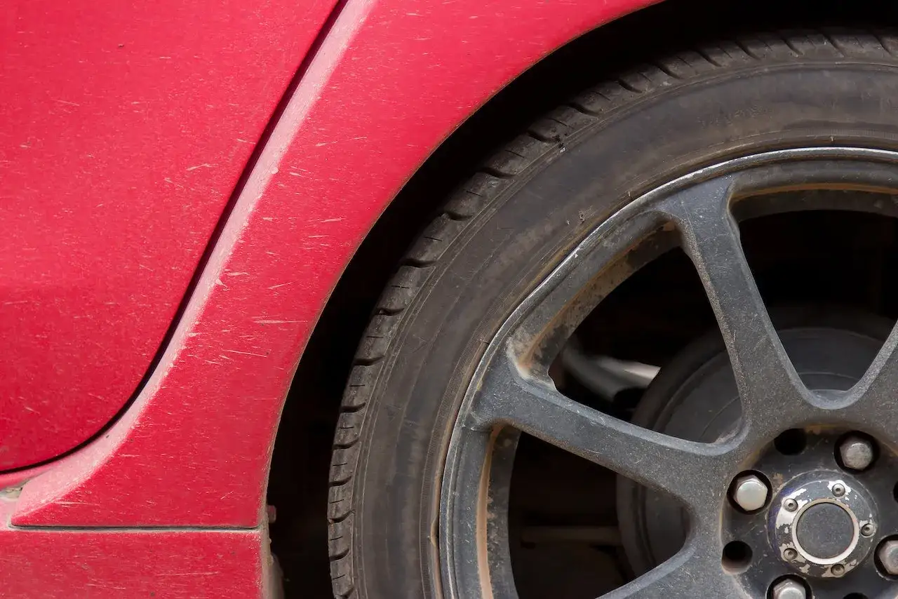 Primer plano de un neumático y llanta de aleación de un coche rojo, mostrando diferentes tipos de ruedas coche.