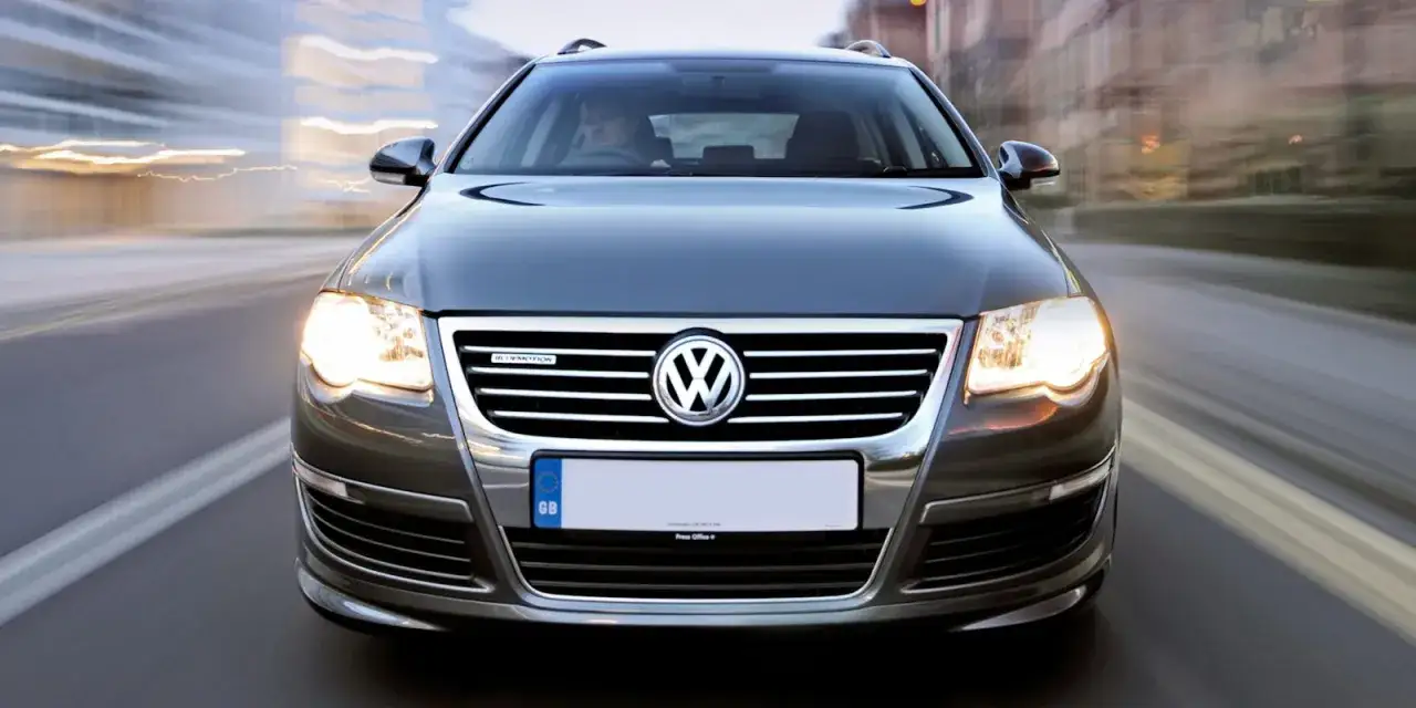 Volkswagen Passat Bluemotion que es: un coche familiar gris en movimiento, con luces encendidas y el logo de Volkswagen en la parrilla.