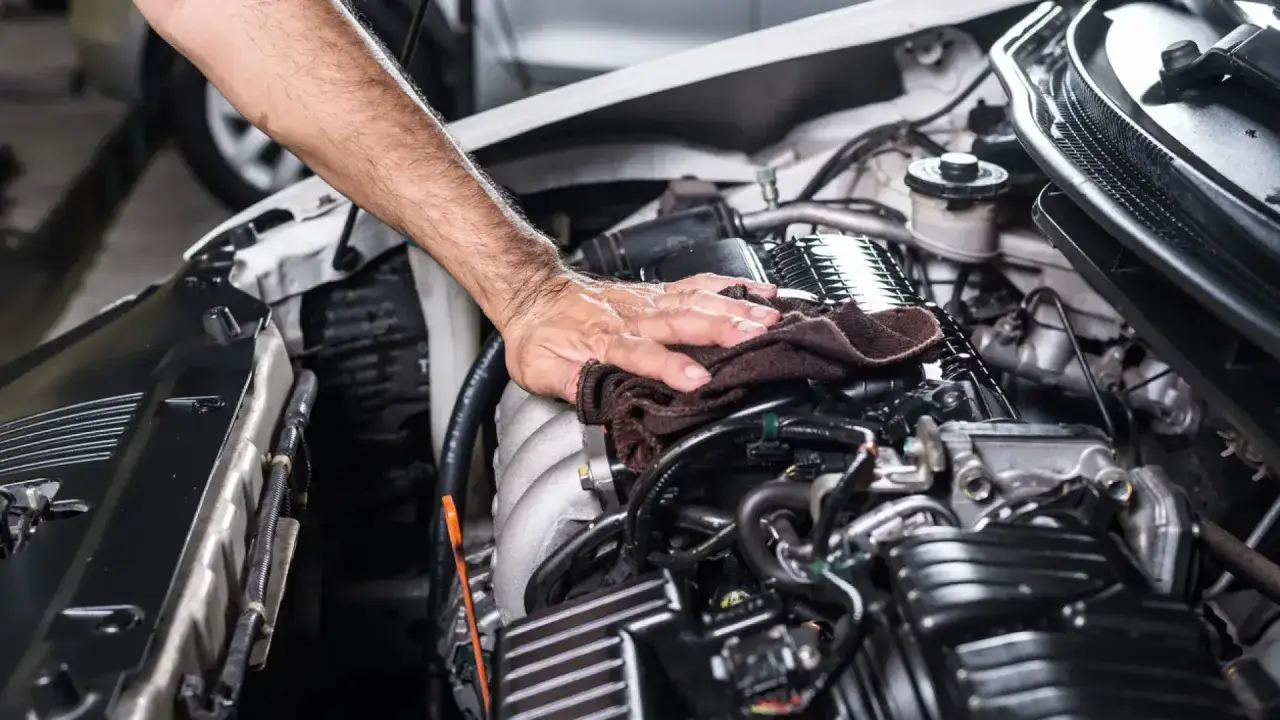 Mano limpiando el motor de un coche diesel. El mantenimiento del coche diesel es esencial para su buen funcionamiento.